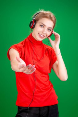 Yeşil arka planda kulaklık takan sarışın kız.