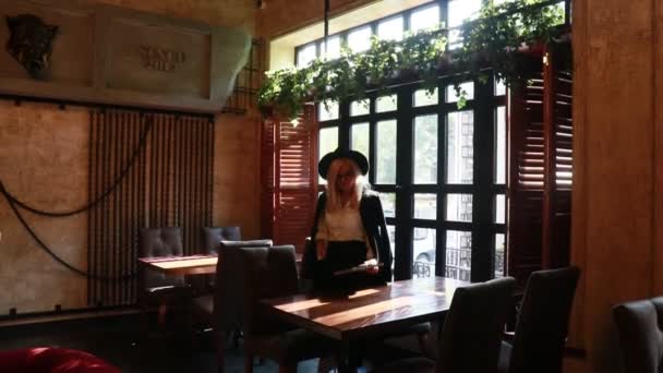 Blond Kvinna Svart Hatt Vid Ett Bord Restaurang — Stockvideo