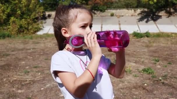 女の子はスポーツ後屋外で水を飲む — ストック動画