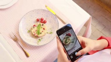 Lokantadaki kız yemek fotoğrafı çekiyor.