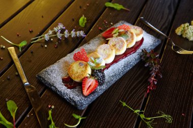 Böğürtlenli ve meyveli cheesecake şeklinde tatlı.