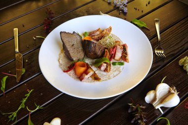 Beyaz bir tabakta sebzeyle pişirilmiş ciğer.