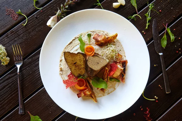 Beyaz bir tabakta sebzeyle pişirilmiş ciğer.