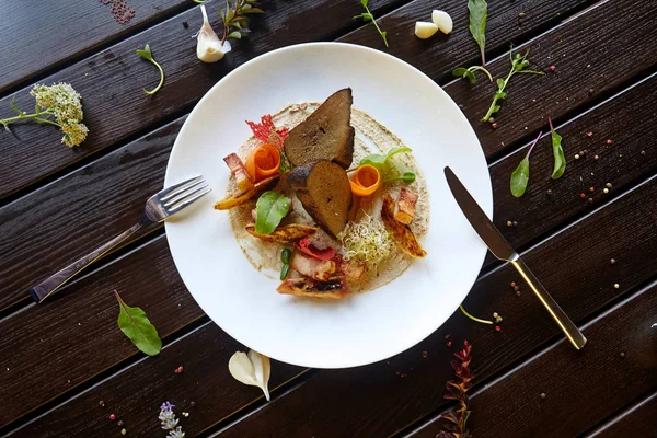 Beyaz bir tabakta sebzeyle pişirilmiş ciğer.