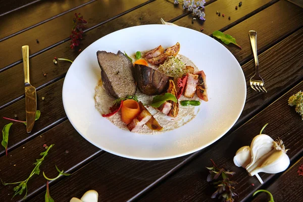 Beyaz bir tabakta sebzeyle pişirilmiş ciğer.