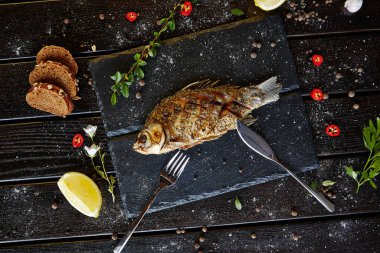 Siyah tahtada limonlu kızarmış balık.