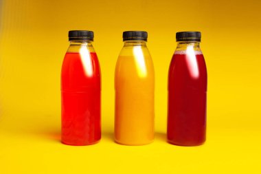 Sarı arka planda farklı renkte içilen üç plastik şişe.