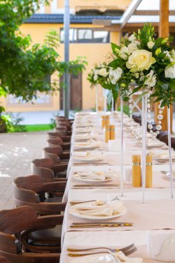 Bir restoranda çiçeklerle süslenmiş masalar ve ekipmanlarla kutlama için masalar hazırladık.