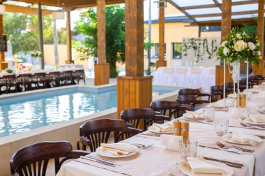 Bir restoranda çiçeklerle süslenmiş masalar ve ekipmanlarla kutlama için masalar hazırladık.