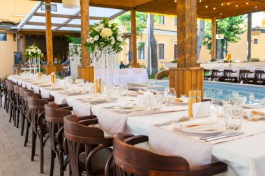 Bir restoranda çiçeklerle süslenmiş masalar ve ekipmanlarla kutlama için masalar hazırladık.