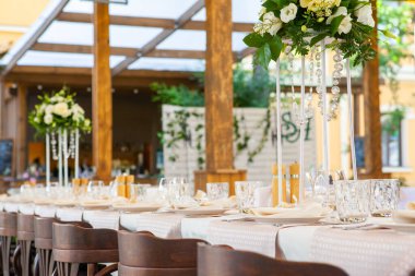 Bir restoranda çiçeklerle süslenmiş masalar ve ekipmanlarla kutlama için masalar hazırladık.