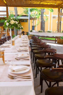 Bir restoranda çiçeklerle süslenmiş masalar ve ekipmanlarla kutlama için masalar hazırladık.