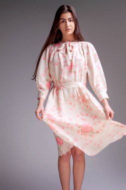 Stüdyoda saçları güzel bir elbiseyle gri arka planda bir kadın manken.