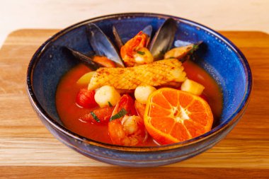 Tabakta çorba ve içindeki malzemeler ahşap bir tahtanın üzerinde.