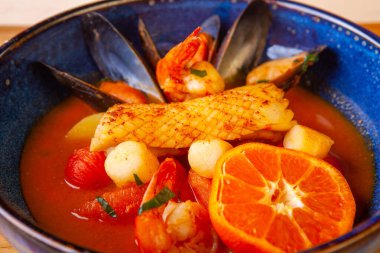 Tabakta çorba ve içindeki malzemeler ahşap bir tahtanın üzerinde.