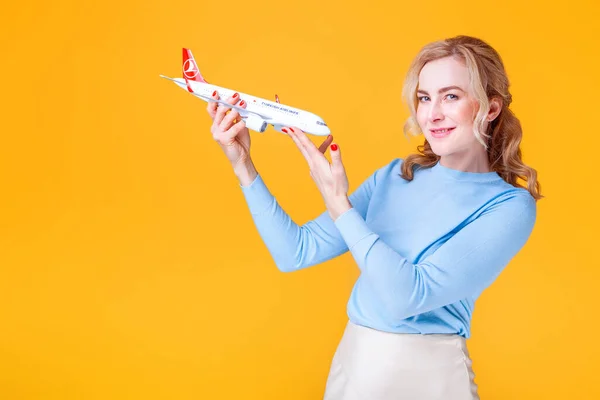 Blondine Mit Weißem Flugzeug Der Hand Vor Gelbem Hintergrund Studio — Stockfoto