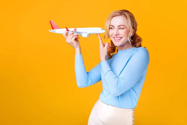 Blondine Mit Weißem Flugzeug Der Hand Vor Gelbem Hintergrund Studio — Stockfoto