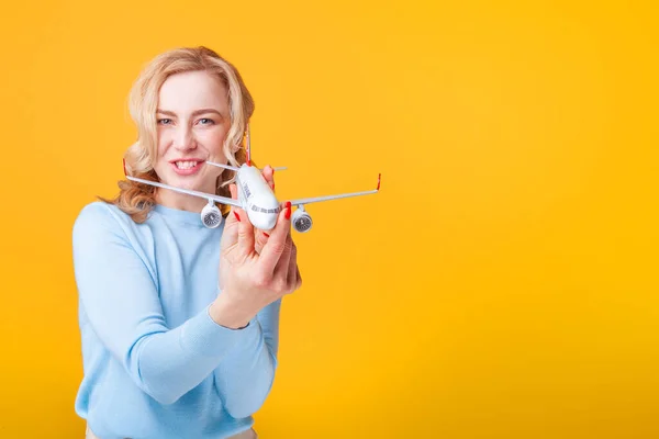 Blondine Mit Weißem Flugzeug Der Hand Vor Gelbem Hintergrund Studio — Stockfoto