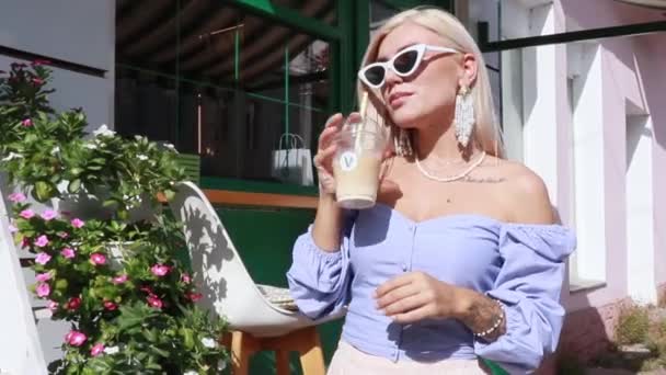 金发女人在街上的咖啡店里喝鸡尾酒 — 图库视频影像