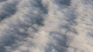 Uçan bir uçağın penceresinden gökyüzü bulutları fırlatıyordu.