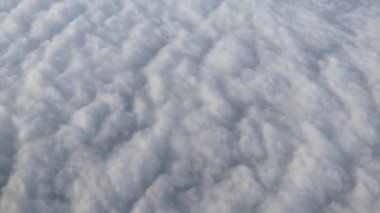 Uçan bir uçağın penceresinden gökyüzü bulutları fırlatıyordu.