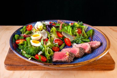 Domates salatası, yumurta ve tabakta dilimlenmiş balık.