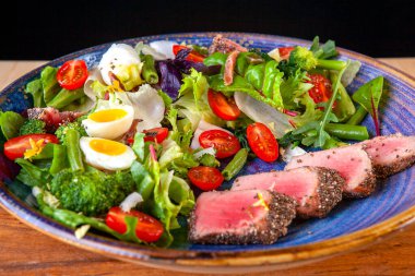 Domates salatası, yumurta ve tabakta dilimlenmiş balık.