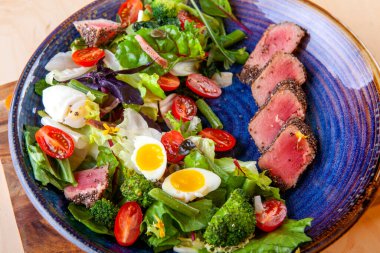 Domates salatası, yumurta ve tabakta dilimlenmiş balık.