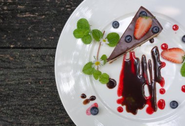 Çilek ve plaka üzerinde ahşap arka plan üstten görünüm üzerinde yaban mersini ile Choccolate Cheesecake