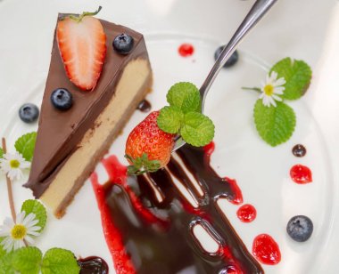 Çilek Choccolate Cheesecake ve Blueberry plaka üzerinde kaşıkla üzerinde