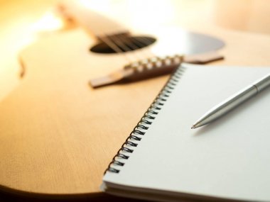 Müzik oluşturma araçları, gitar, defter ve kalem ahşap arka plan üzerinde