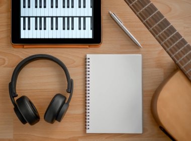 Müzik oluşturma araçları, kulaklık, gitar, Notebook, elektronik Tablet ve kalem üzerinde ahşap arka plan Üstten Görünüm