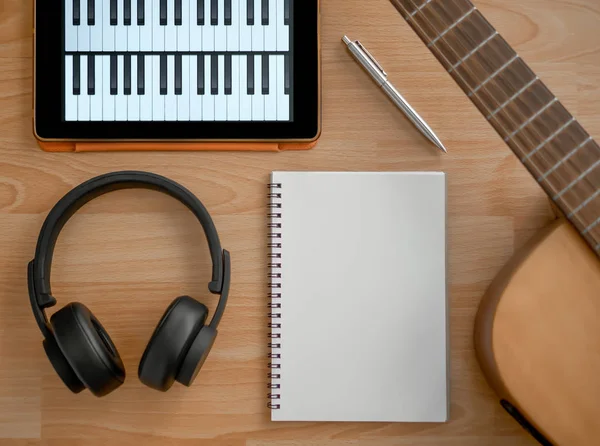 Müzik oluşturma araçları, kulaklık, gitar, Notebook, elektronik Tablet ve kalem üzerinde ahşap arka plan Üstten Görünüm