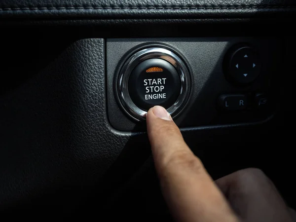 Кнопка запуска-остановки двигателя с оранжевым светом на черной автомобильной консоли — стоковое фото
