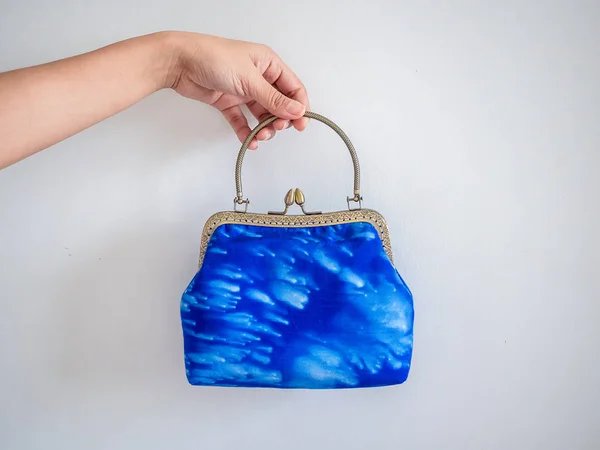 Hand holding beautiful vintage purse made by indigo blue fabric.