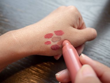 Kadının elleri cildindeki ruj renklerini test ediyor..