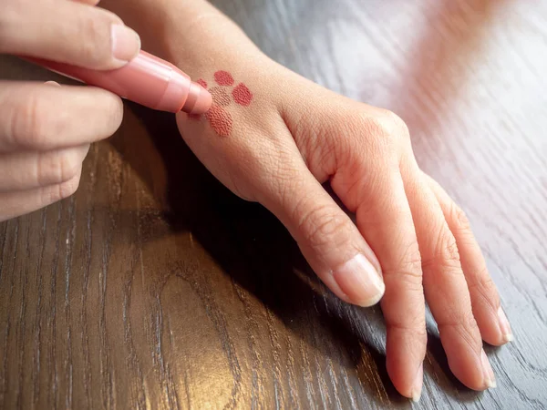 Женские руки проверяют цвета помады на коже . — стоковое фото