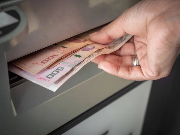 Hand receiving cash money from ATM machine.