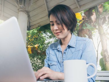 Kafede dizüstü bilgisayar kullanan güzel mutlu Asyalı kadın..