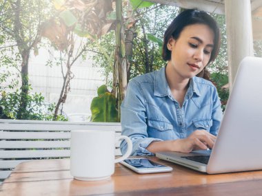 Kafede dizüstü bilgisayar kullanan güzel mutlu Asyalı kadın..