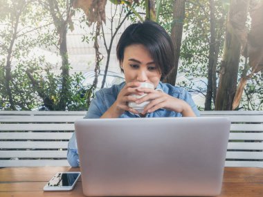 Kafede dizüstü bilgisayar kullanan güzel mutlu Asyalı kadın..