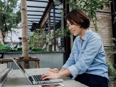 Güzel, mutlu Asyalı kadın kısa saçlı, kot pantolon giyen. 