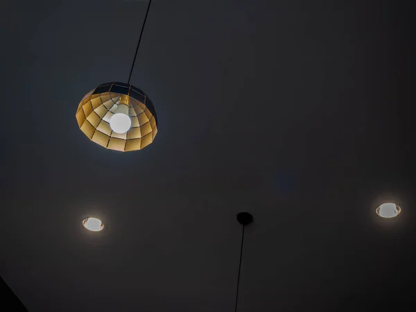 コピースペースのある暗い部屋の光で天井から吊るされたモダンな天井の光 — ストック写真