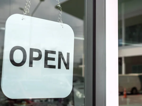 White open sign hanging on the glass door of coffee shop, close-up.