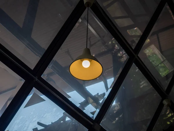 Modern ceiling light or light bulb hanging from ceiling in glass house construction building. Retro lighting decoration.