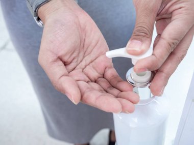 Yakın plan el, alkollü el jölesiyle plastik şişe pompası basıyor. El dezenfektanı, jel temizleme, alkol masajı..