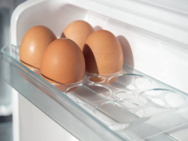 Beyaz buzdolabında dört taze tavuk yumurtası..