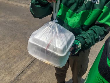 Bangkok, Tayland - 30 Mart 2020 Kap Yiyecek Teslimatı motosikletli adam yiyecek teslimatı için Grab, akıllı telefondan ünlü uygulama.