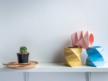 Kaktüs tenceresi. Beton çömlek. Üç boş mavi, pembe ve sarı modern geometrik beton ekici ve yeşil kaktüs beyaz arka planda izole edilmiş ahşap bir rafta ahşap bir kabın üzerinde..