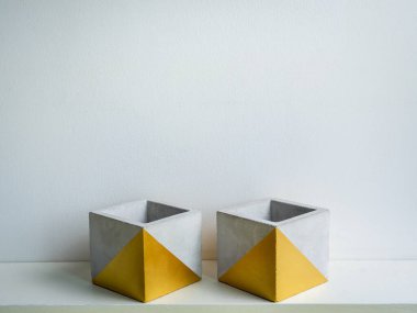 Kaktüs tenceresi. Beton çömlek. Beyaz ahşap raflara altın boyalı iki boş modern geometrik beton ekici beyaz arka planda izole edilmiş..